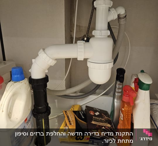 כיור עם צנרת ומוצרי ניקוי מתחת לכיור